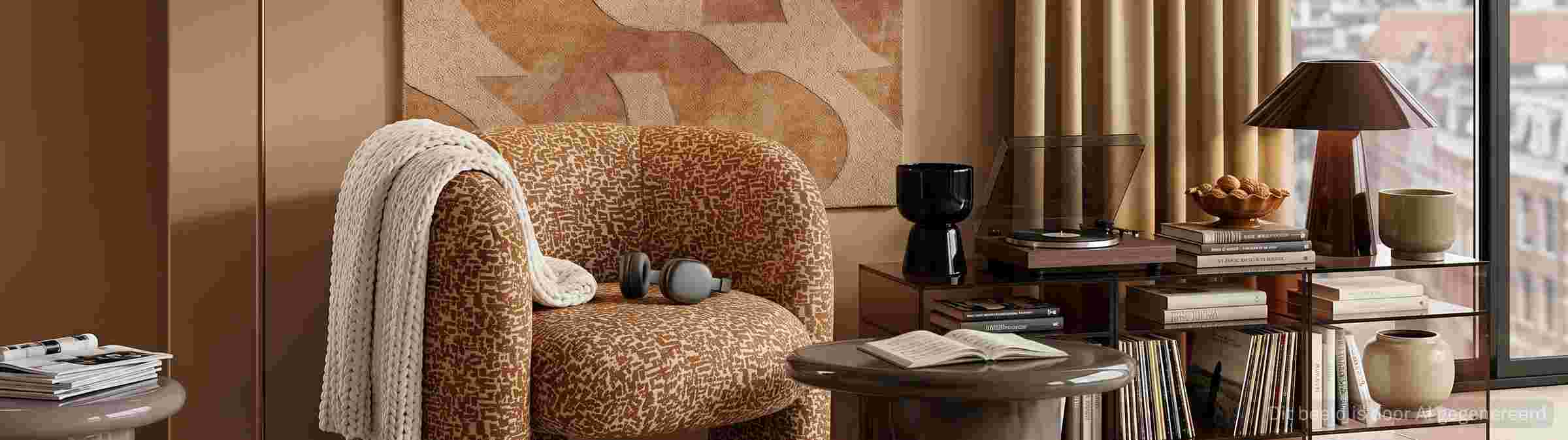 Gezellige woonkamer met bruine fauteuil, gebreid plaid, houten mediakast, platenspeler en warme aardtinten.
