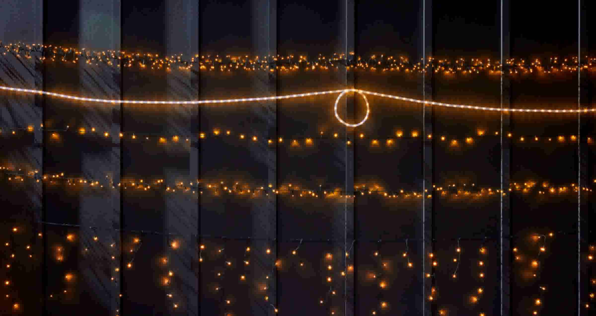 Warme gouden lichtjes in horizontale rijen tegen een donkere achtergrond, met een verlichte cirkel in het midden.