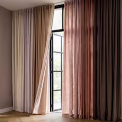 Gordijnen in beige, roze en bruin bij een hoog raam met natuurlijk licht in een moderne kamer.