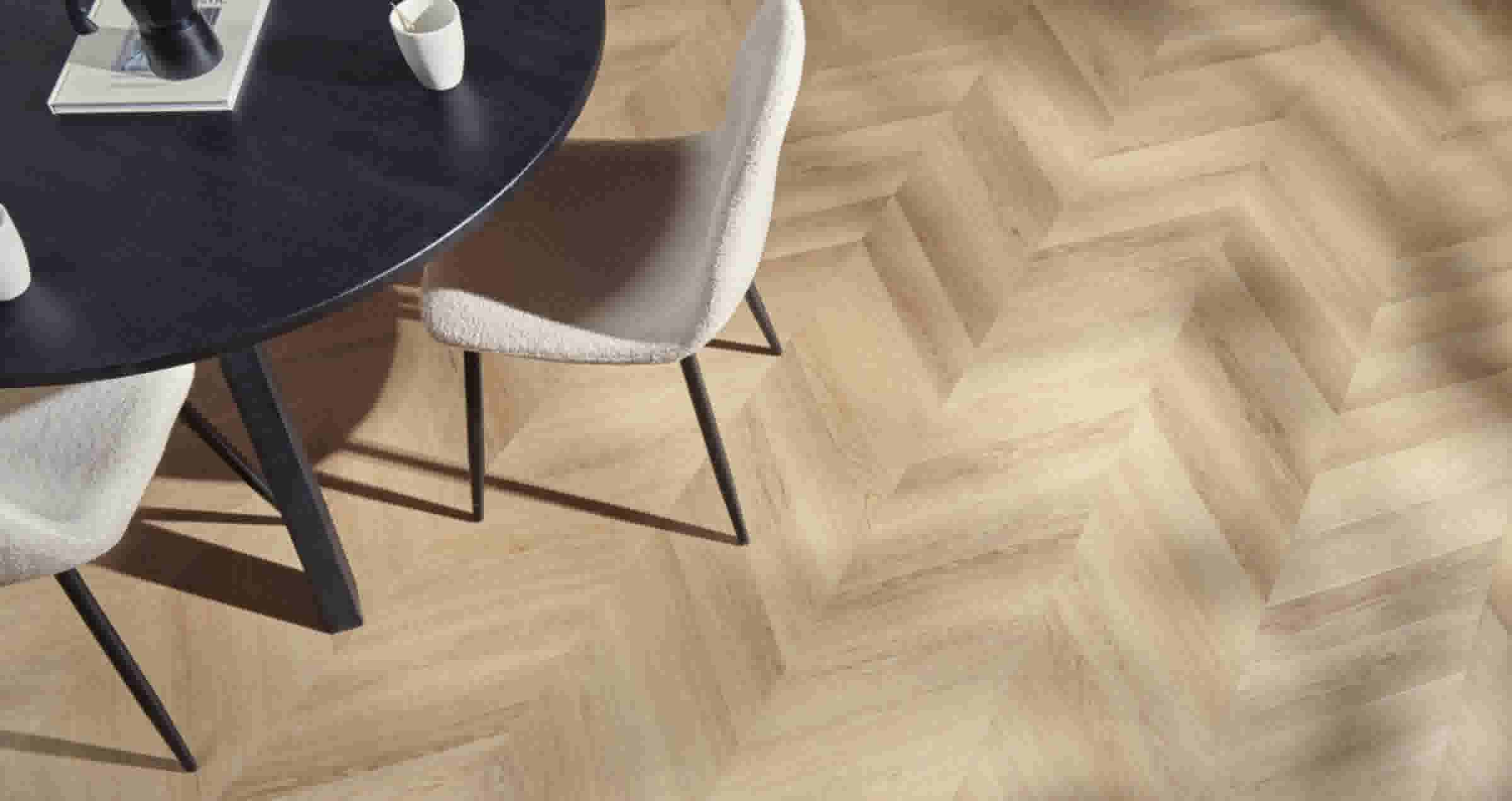 Moderne eetkamer met zwarte ronde tafel en beige stoelen op een lichthouten pvc vloer met een hongaarse punt