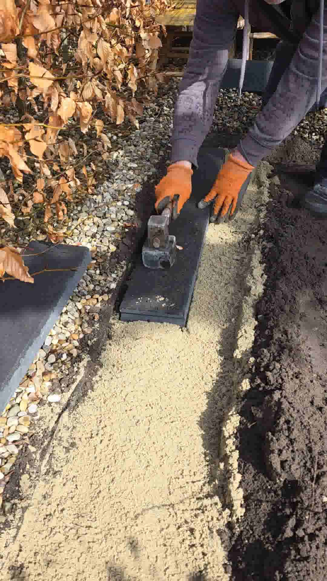 Persoon met oranje handschoenen maakt het ophoogzand goed plat