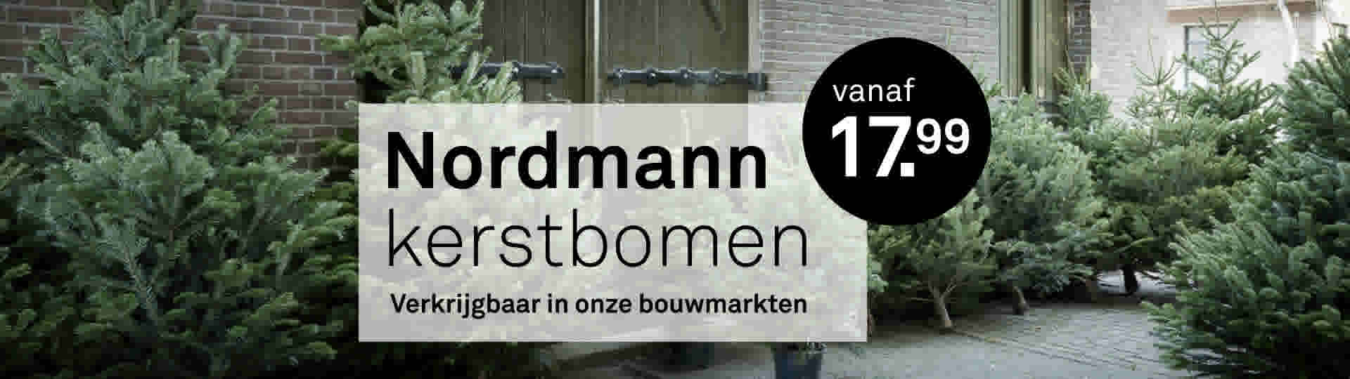 Kerstbomen te koop bij Nordmann vanaf 28 november, getoond voor een bakstenen gebouw met groene deur.