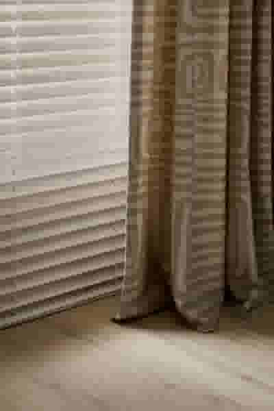 Houten jaloezieën gecombineerd met een beige gordijn met patroon.