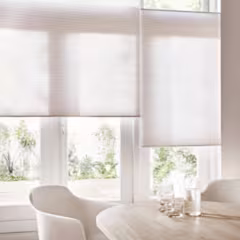 maatwerk plisségordijnen voor een raam met stoelen en eettafel ervoor