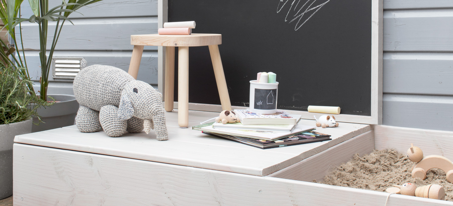 Speelhuisje met een zandbak en krijtbord