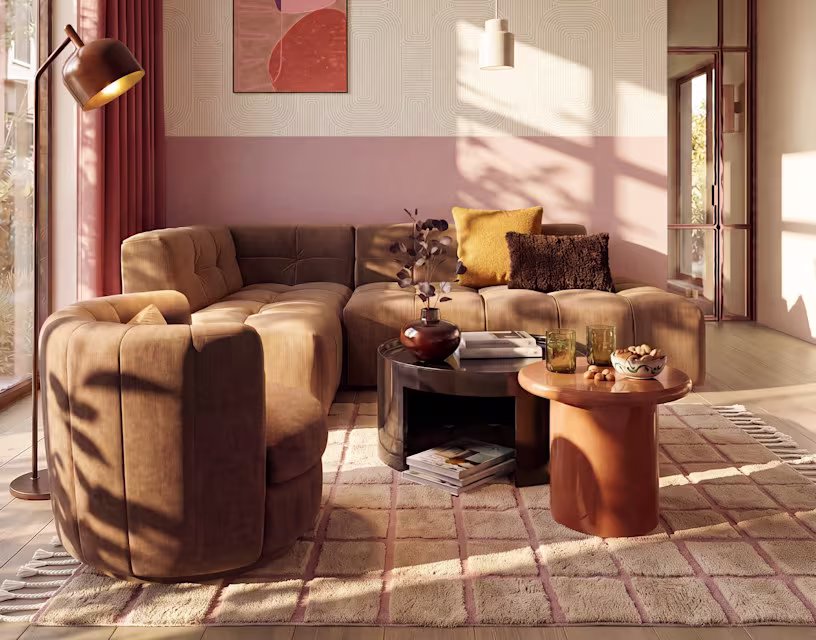 Moderne woonkamer met beige modulaire bank, roze muur, koperen staande lamp en ronde salontafels in zonlicht