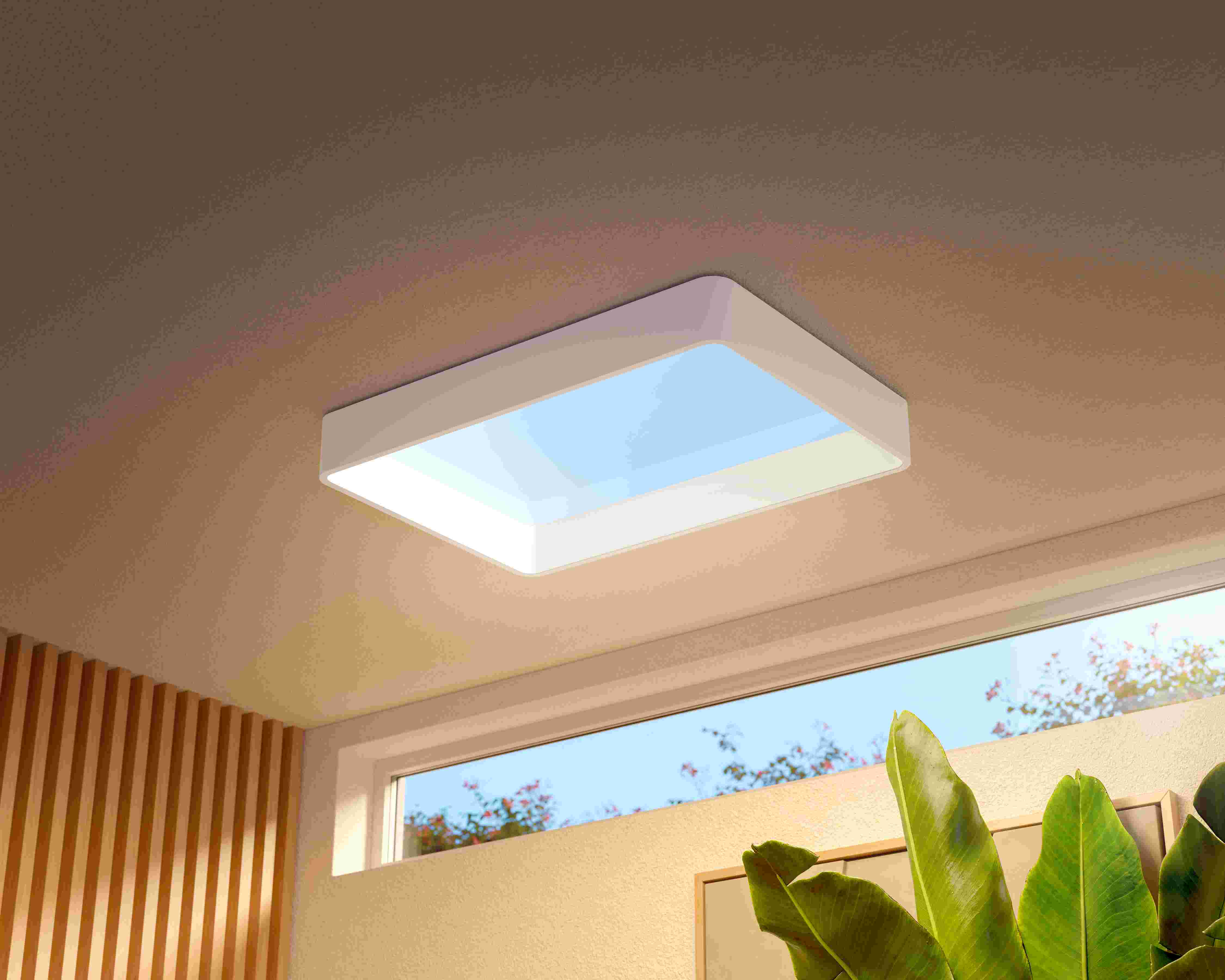 Witte rechthoekige plafondlamp met blauw licht in een warme kamer met houten lamellen, een raam en een groene plant.