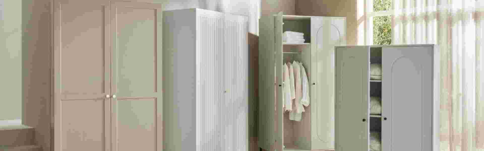 Lichte slaapkamer met witte garderobekasten, één open met hangende kleding en opgevouwen textiel op de planken.