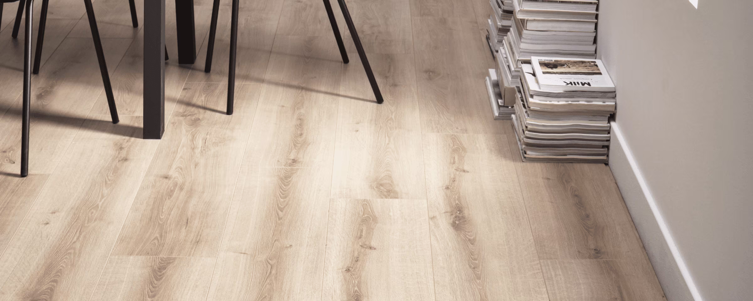 Lichte houten vloer met stoelpoten en stapel tijdschriften, roze promotiebord toont 60% korting.