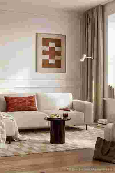Moderne woonkamer met beige bank, geometrisch wandkunst, bruine salontafel en neutrale tinten met warme accenten.