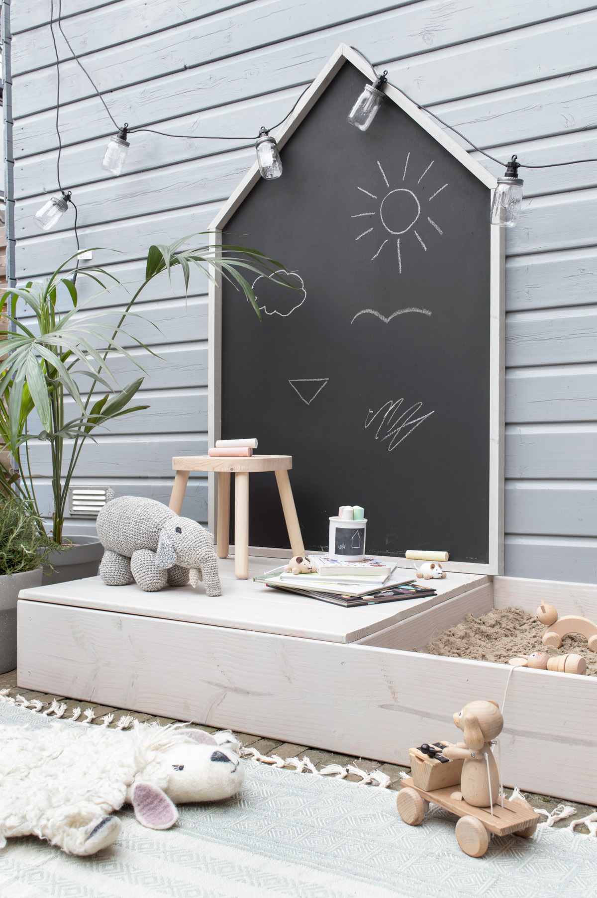 Zandbak met een krukje, krijt, boeken en een knuffelolifant