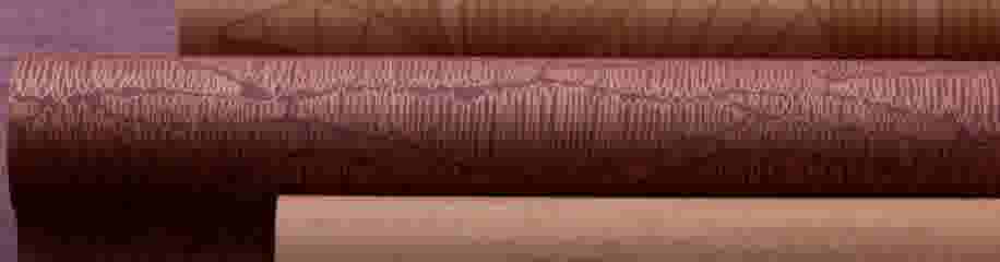 Opgerolde behangrollen in verschillende tinten bruin en paars met decoratieve golfpatronen, naast elkaar gerangschikt.