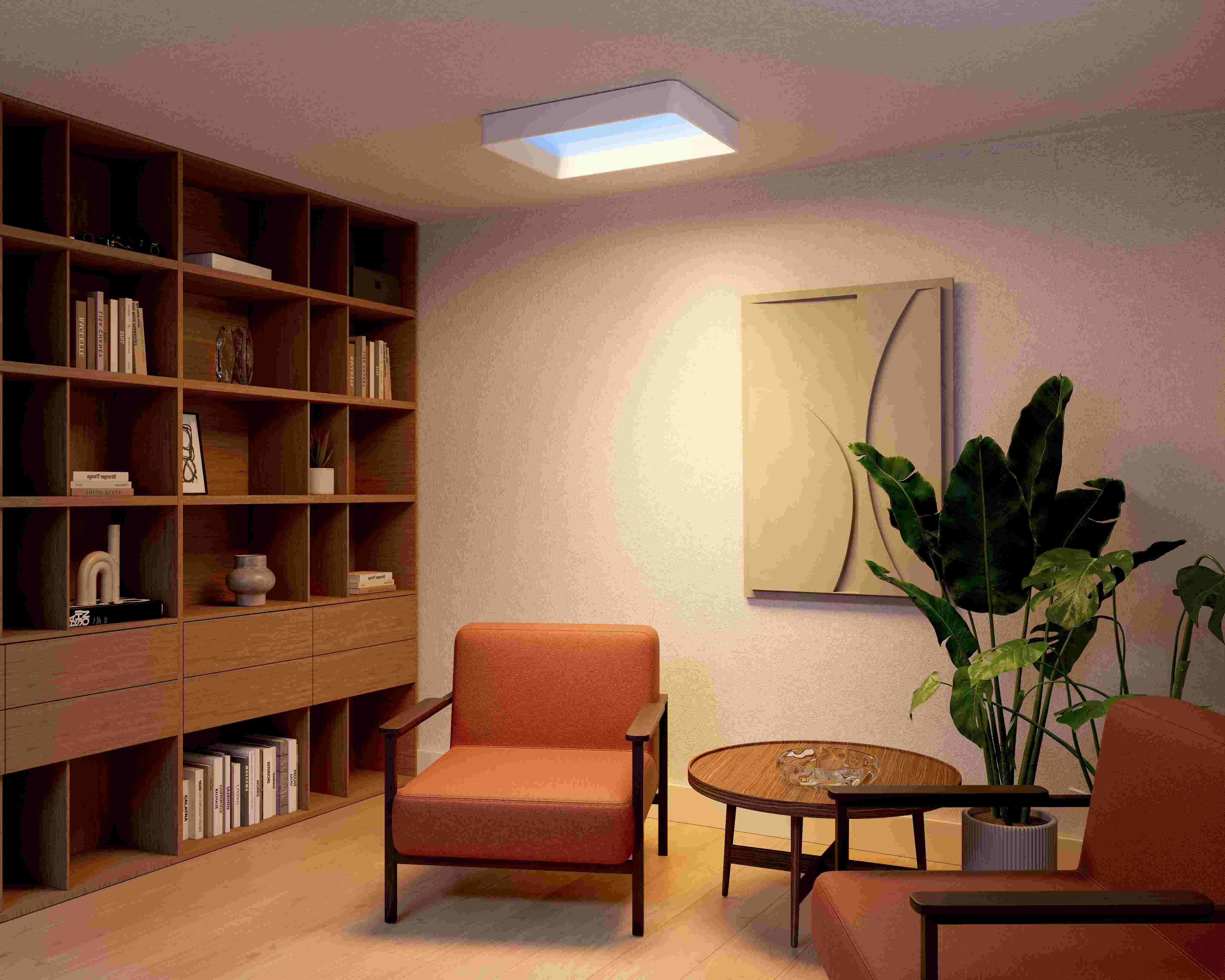 Gezellige woonkamer met oranje fauteuil, houten boekenkast en een vierkante plafondlamp die warm licht verspreidt.