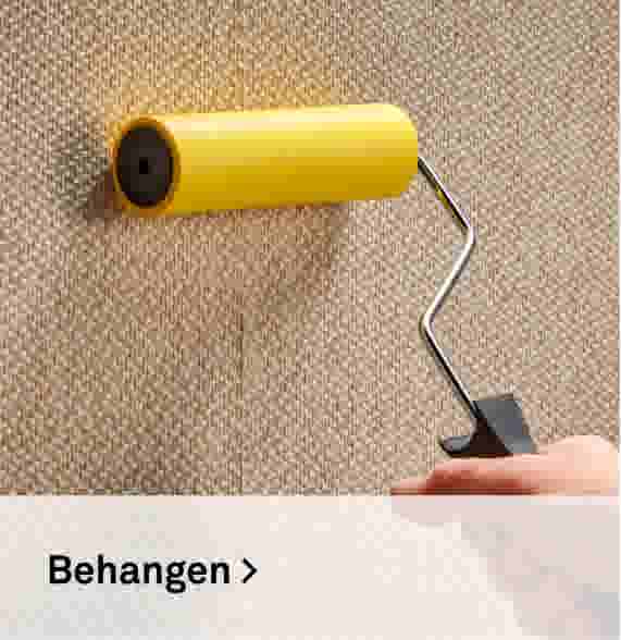 Behangen. Sfeerbeeld van een hand met een gele lijmroller op behang.