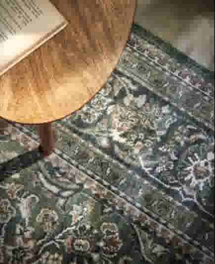 Donkergroen vloerkleed met patronen onder een houten koffietafel