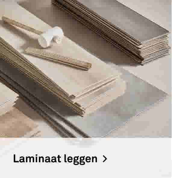 Laminaat leggen. Sfeerbeeld van stapels laminaatplanken in verschillende houttinten met een klopblok en meetlat.