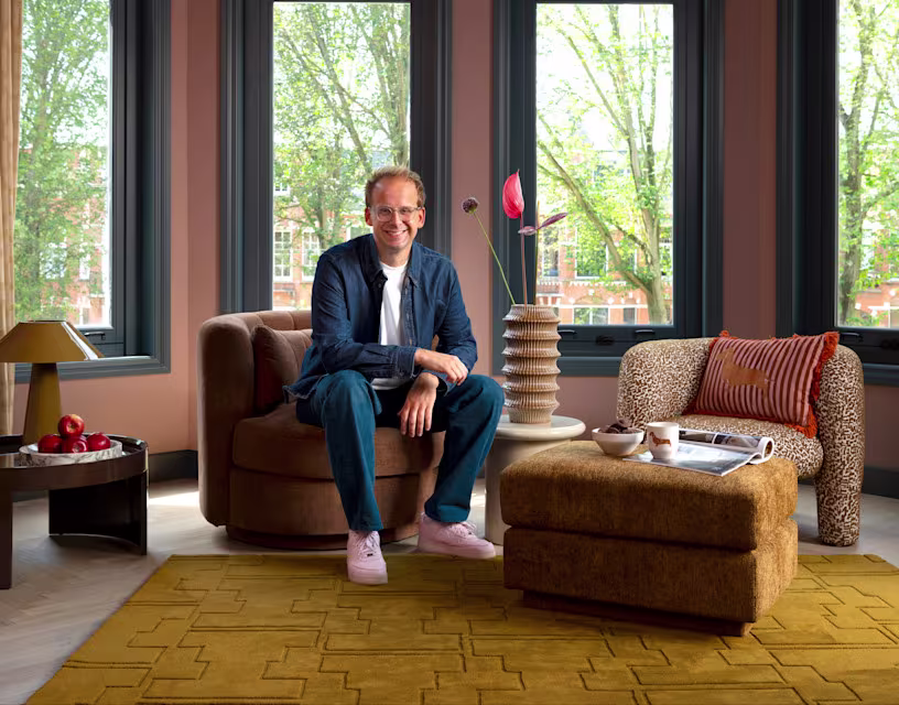 Theo-Bert Pot in woonkamer met fauteuils, hocker, vloerkleed en woonaccessoires uit zijn nieuwe collectie