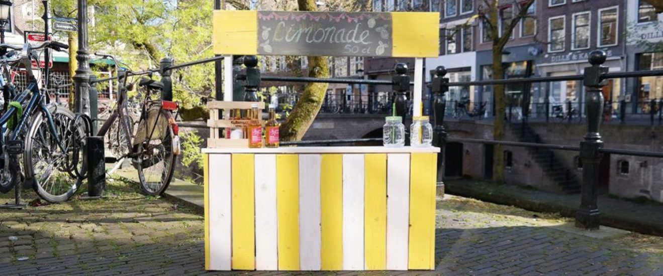 geel-witte limonadekraam op de stoep