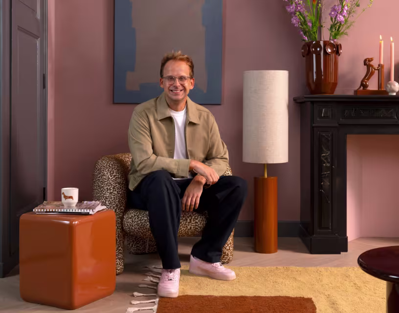 Theo-Bert Pot in woonkamer met vloerlamp, fauteuil, salontafel, vloerkleed en woonaccessoires uit zijn nieuwe collectie