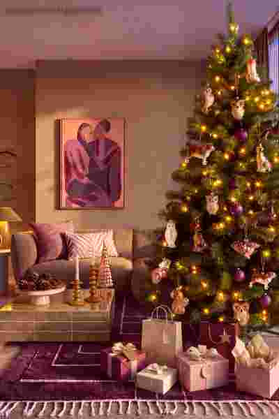 Warme bohemian woonkamer met een prachtig opgetuigde kerstboom met veel cadeaus, helemaal in de country joy wooninspiratie