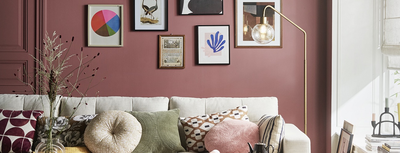 Woonkamer met lichte bank, terracotta muur en verschillende fotolijsten aan de muur