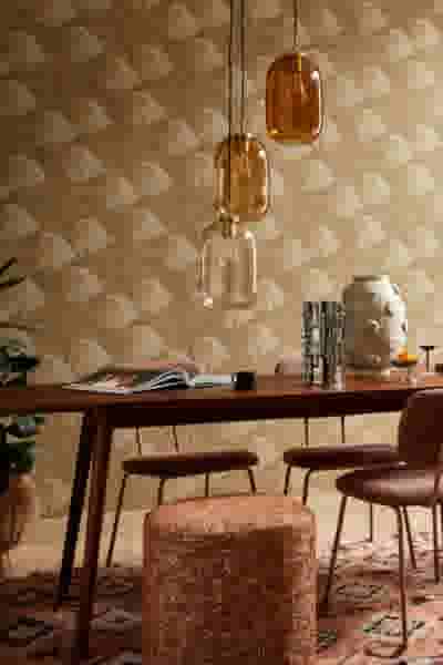 Moderne eetkamer met amberkleurige hangende lampen, houten tafel en stoelen tegen een beige behang met waaierpatroon.