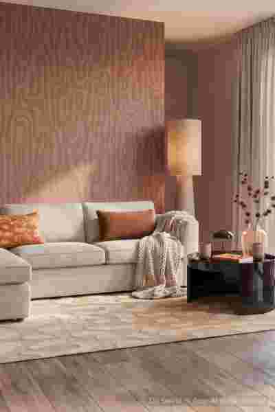 Moderne woonkamer met beige bank, roze wandpaneel, staande lamp en decoratieve kussens in warme tinten.