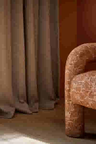 Warmbruine gordijnen gecombineerd met een stijlvolle fauteuil in aardetinten