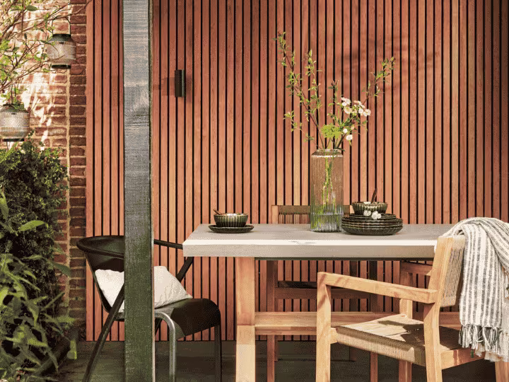 een lattenwand buiten in de tuin met een tuinset