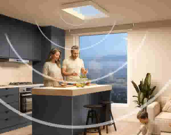 Stel en vrouw bereiden samen een salade in een moderne keuken met dakraam. Een kind speelt op de bank. Lichtstromen zijn zichtbaar.