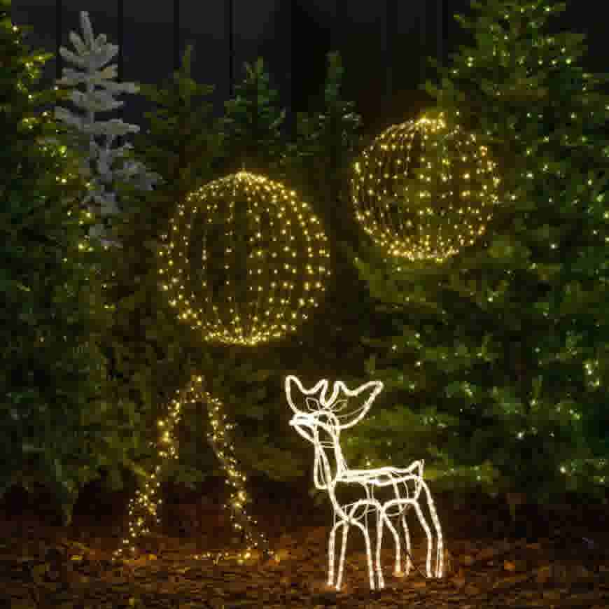 Feestelijke kerstdecoratie met verlichte kerstbomen, twee grote lichtbollen en een lichtgevend rendier op een donkere ondergrond.