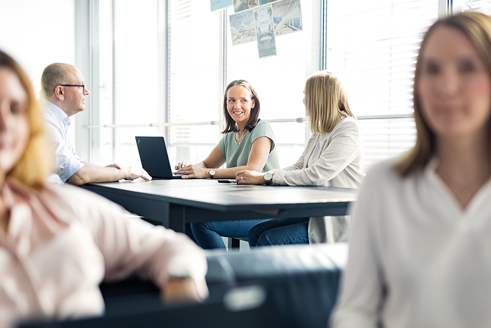 Drei Personen am Tisch, die sich unterhalten 