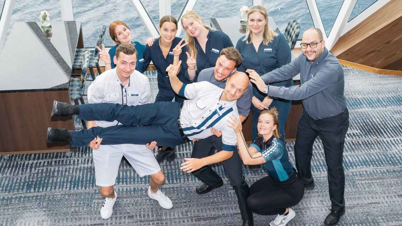8 Personen auf einem Schiff, die eine Person auf Händen tragen