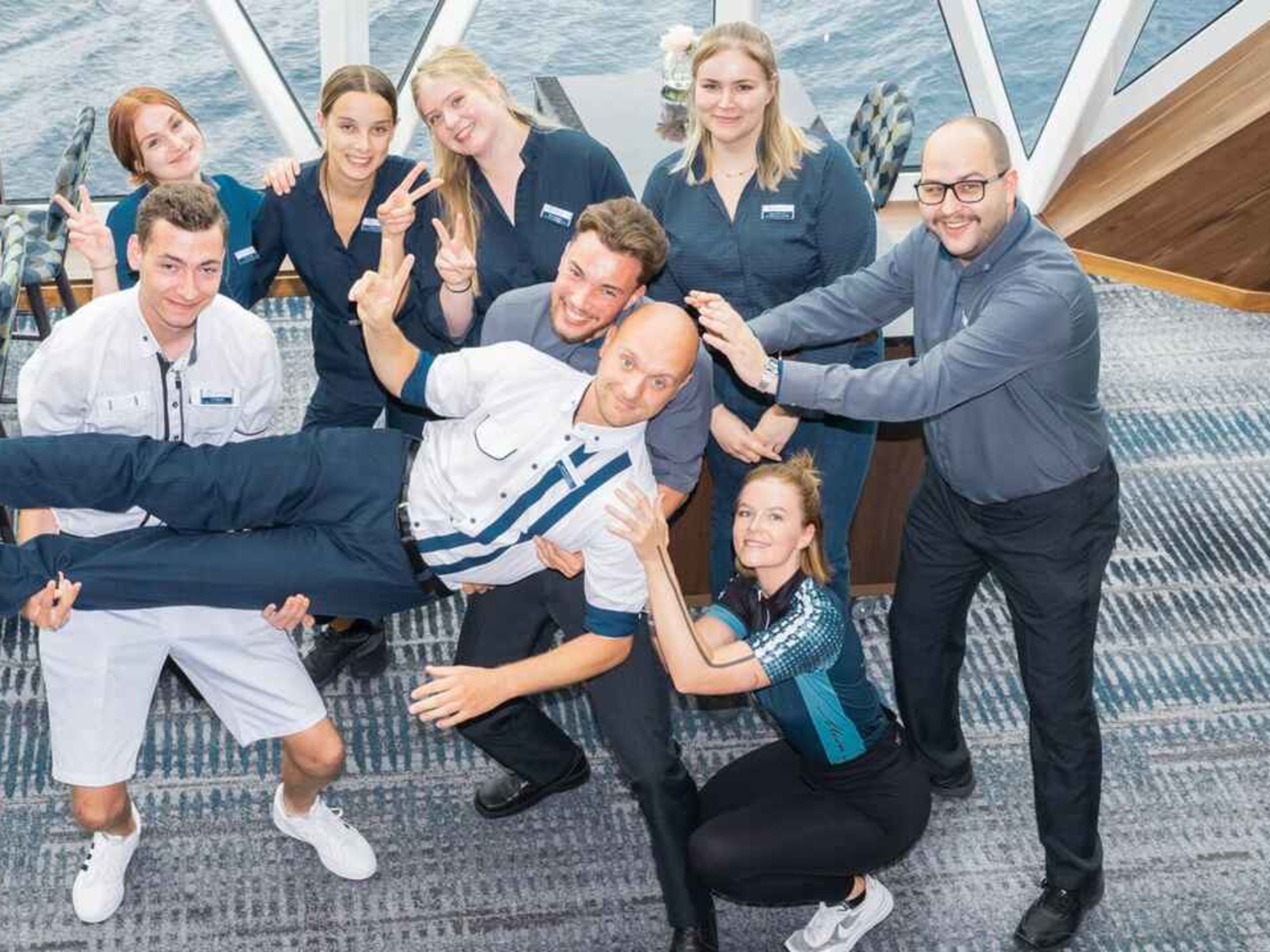 8 Personen auf einem Schiff, die eine Person auf Händen tragen