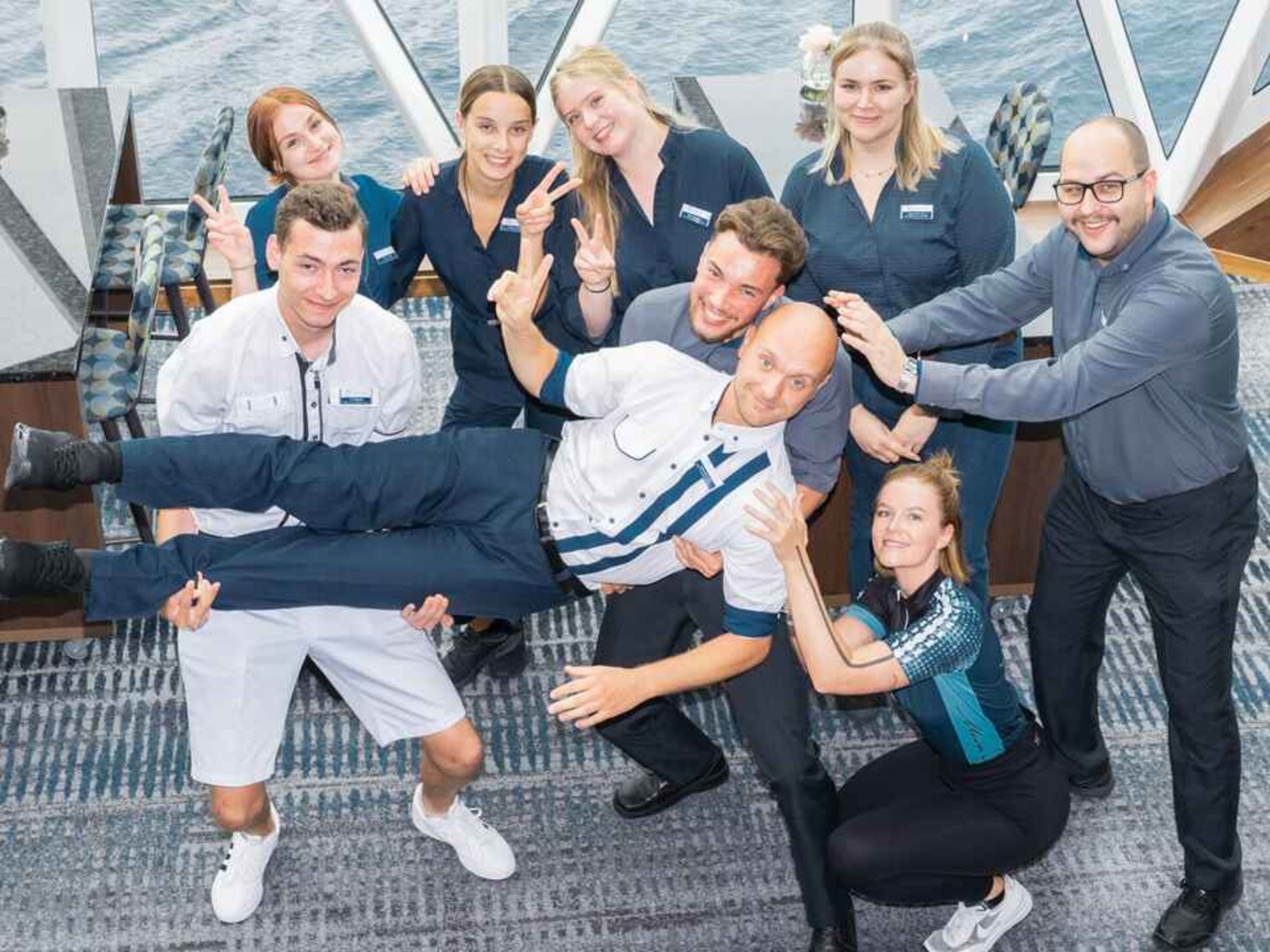 8 Personen auf einem Schiff, die eine Person auf Händen tragen