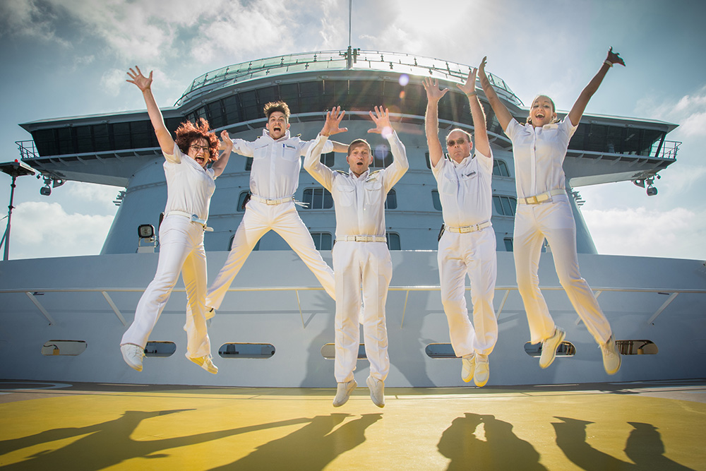 Außendeck vorn am Schiff. Fünf Crew Member springen in die Luft. 