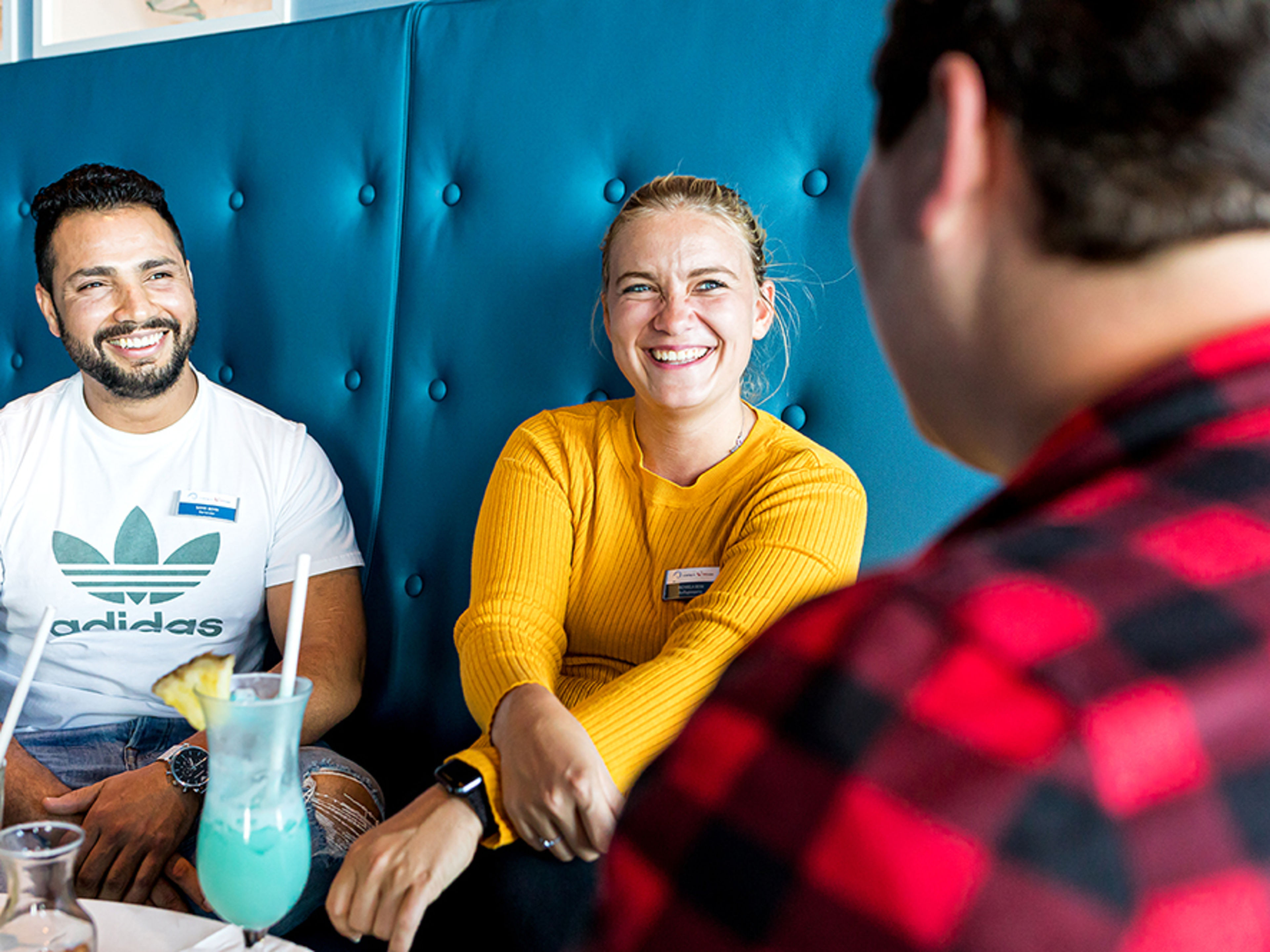 Drei Crew Member sitzen in privater Alltagskleidung in einer Bar.