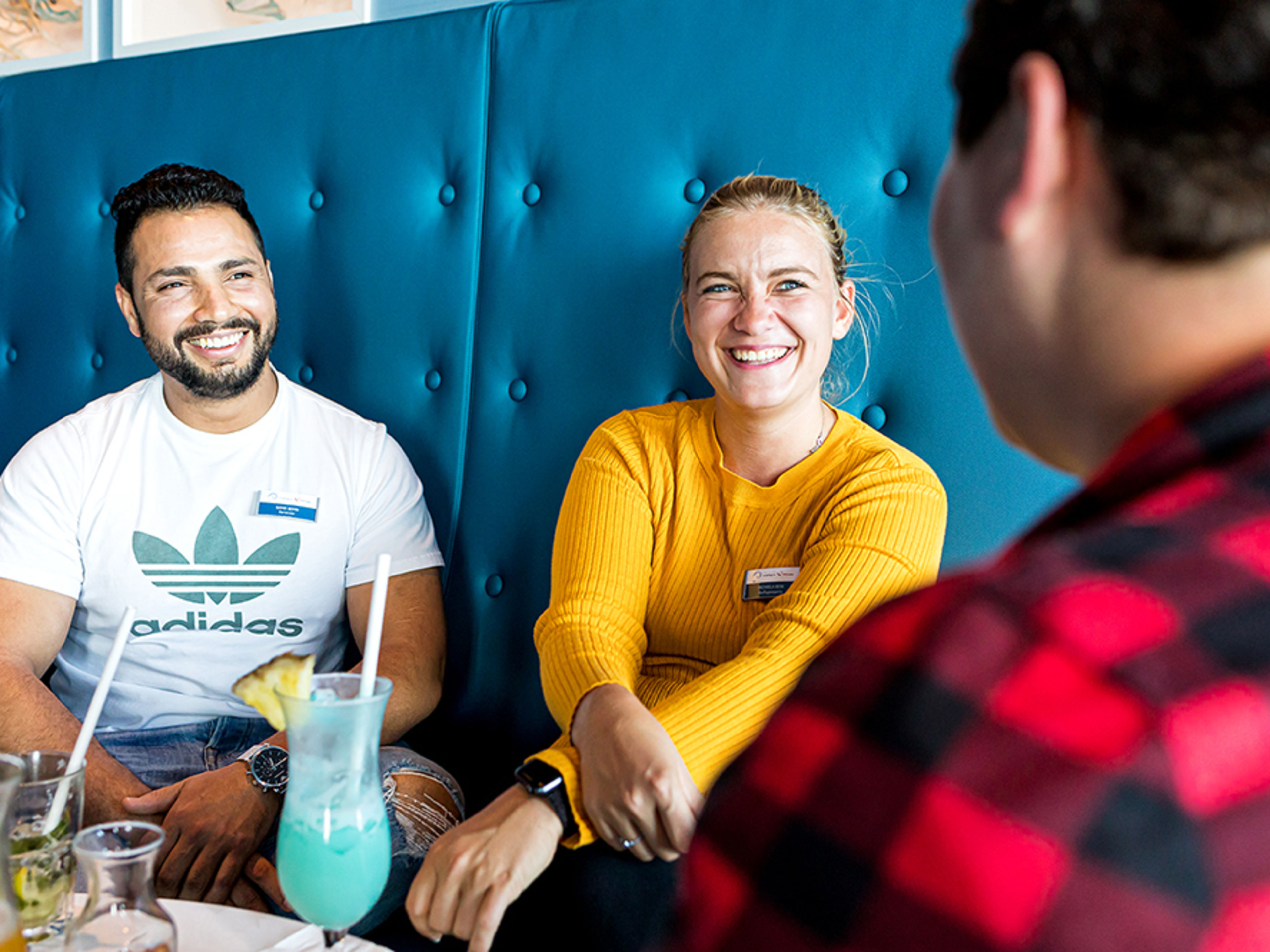 Drei Crew Member sitzen in privater Alltagskleidung in einer Bar.