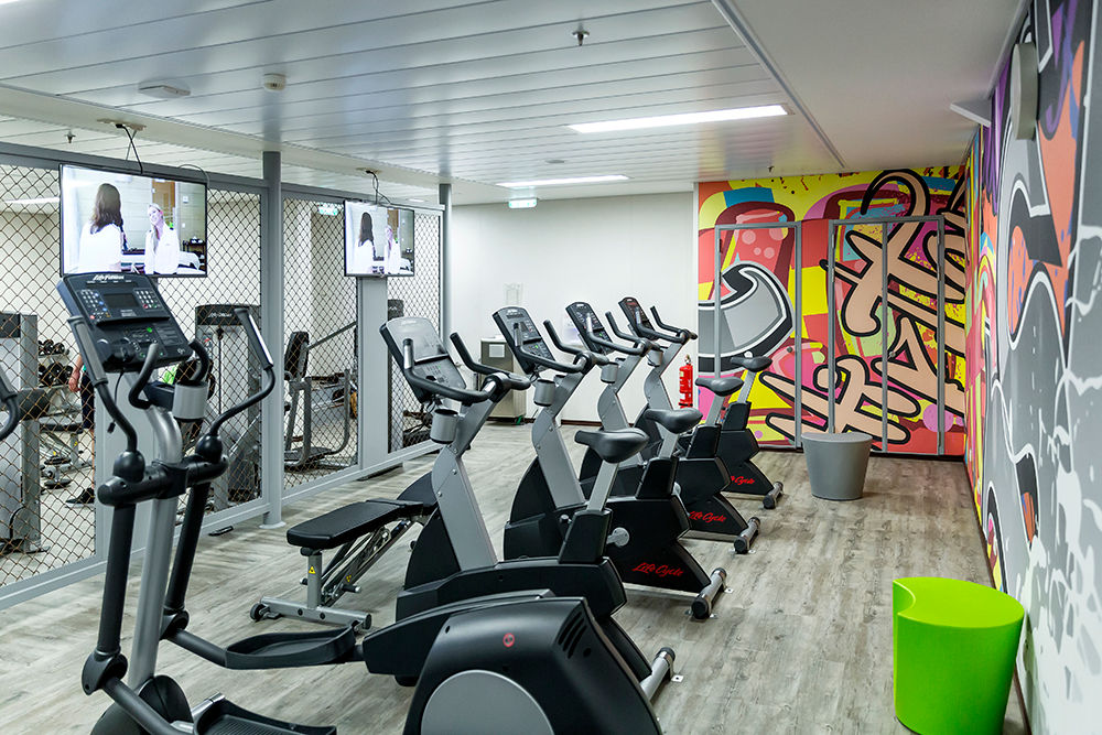 Ein Raum mit bunt gestalteten Wänden und verschiedenen Fitnessgeräten. 