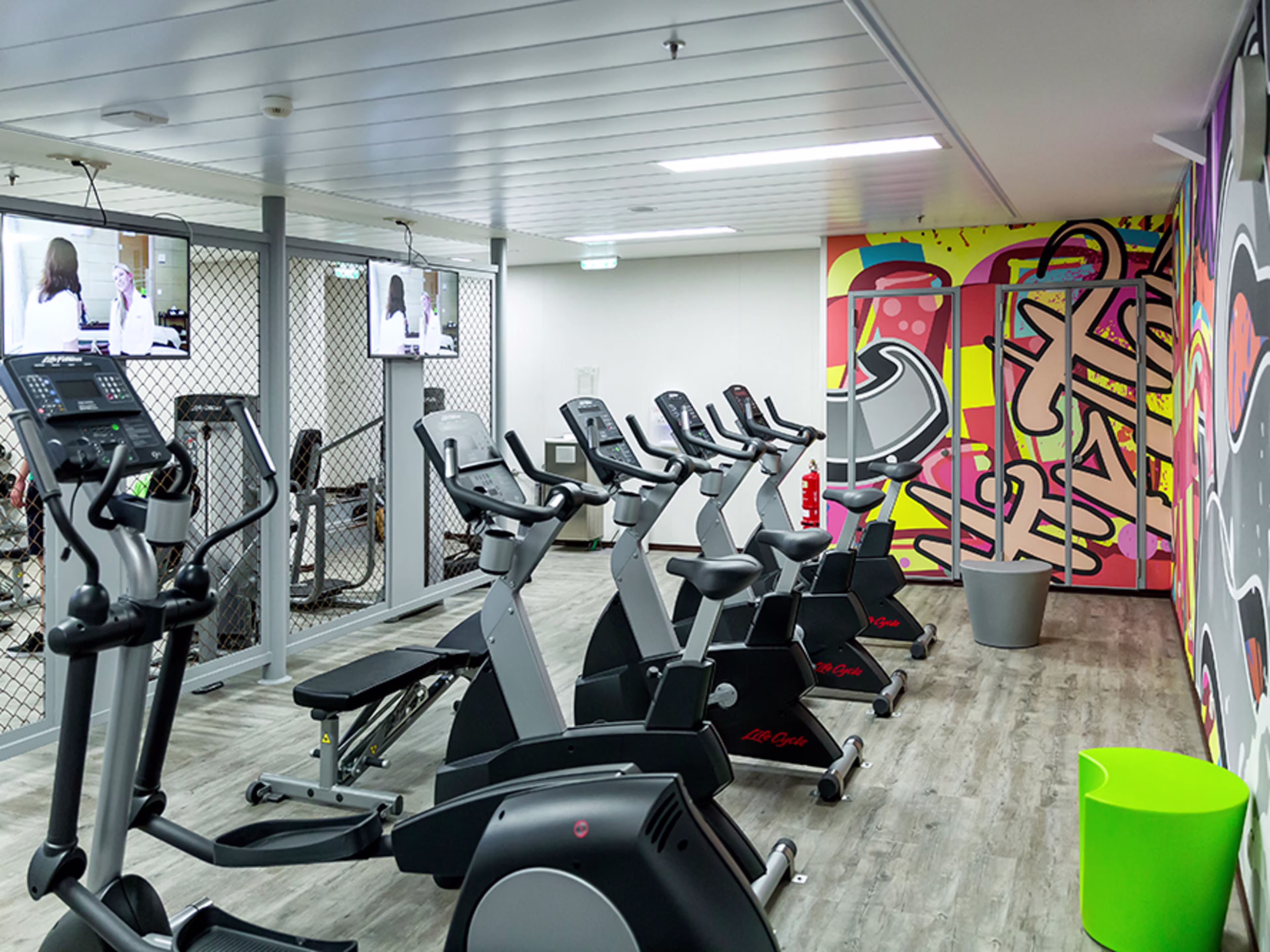 Ein Raum mit bunt gestalteten Wänden und verschiedenen Fitnessgeräten.
