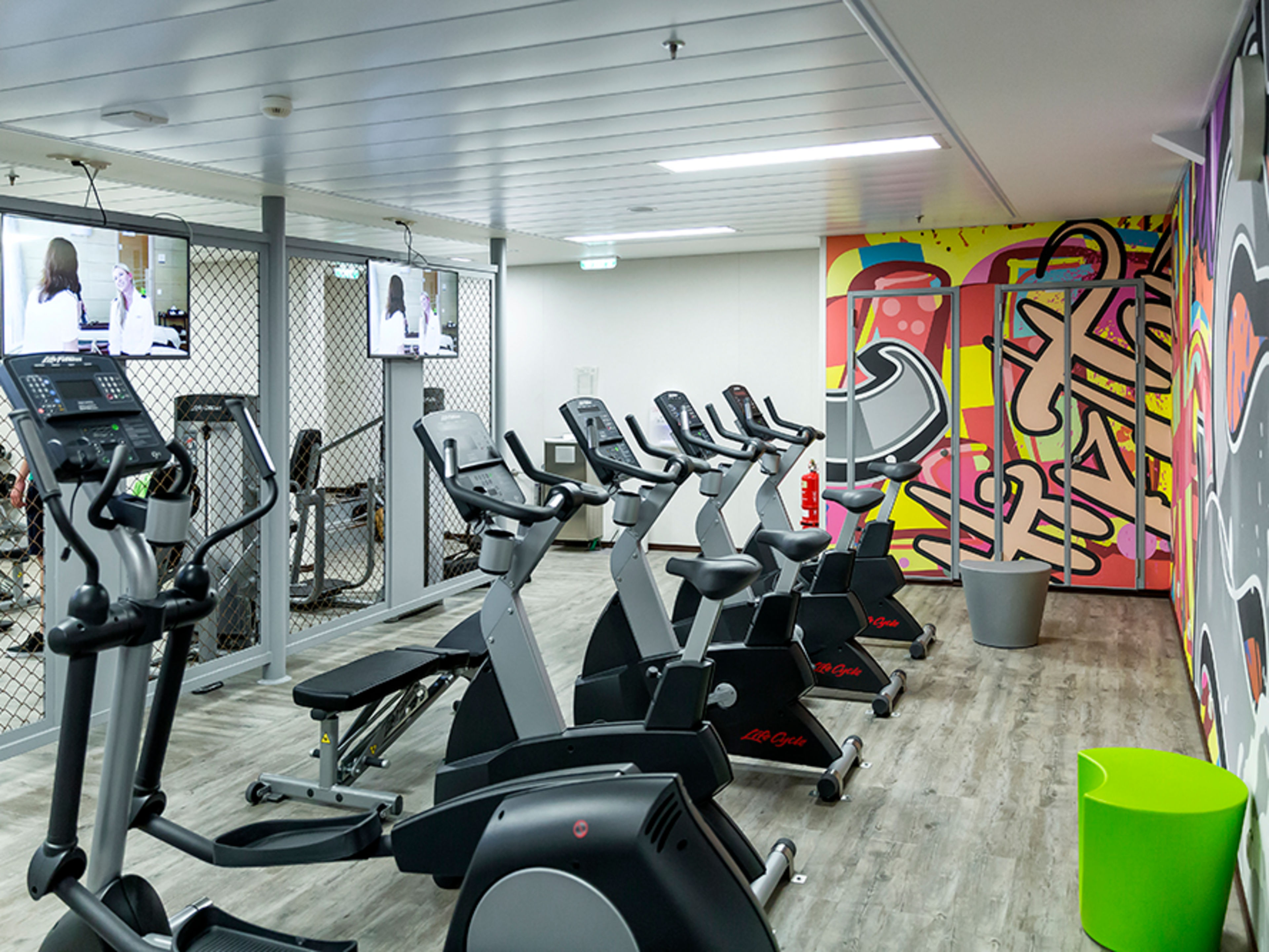 Ein Raum mit bunt gestalteten Wänden und verschiedenen Fitnessgeräten.