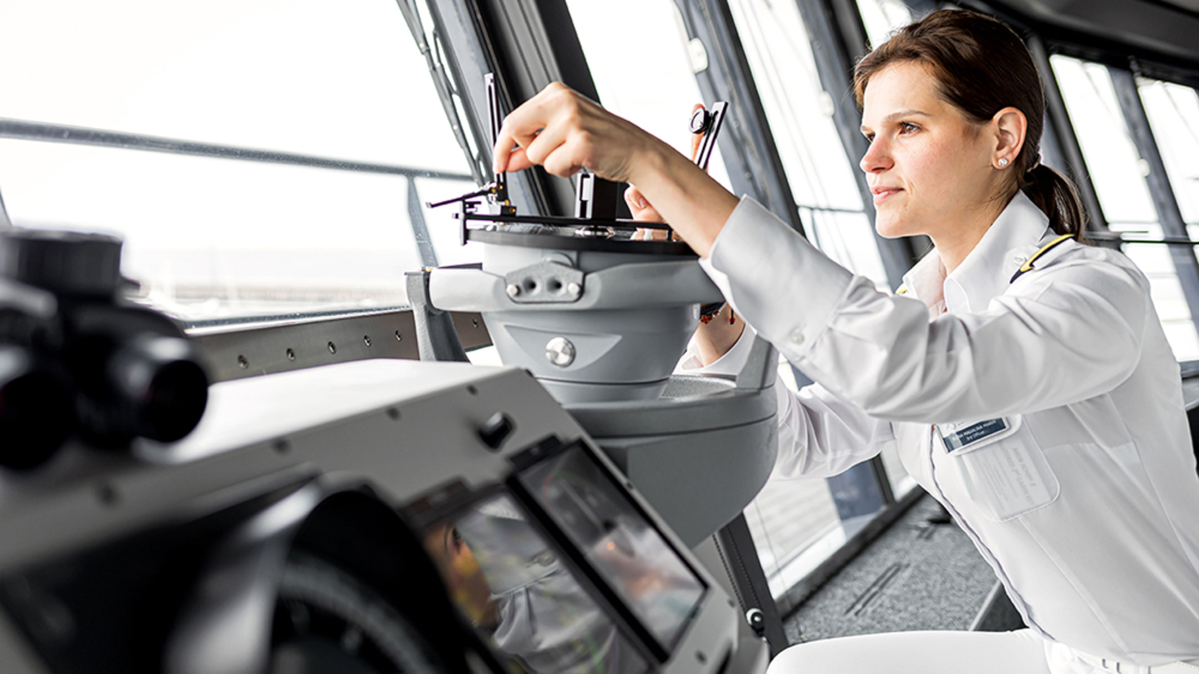 Schiffsbrücke. eine weibliche Offizierin arbeitet konzentriert an einem Navigationsinstrument