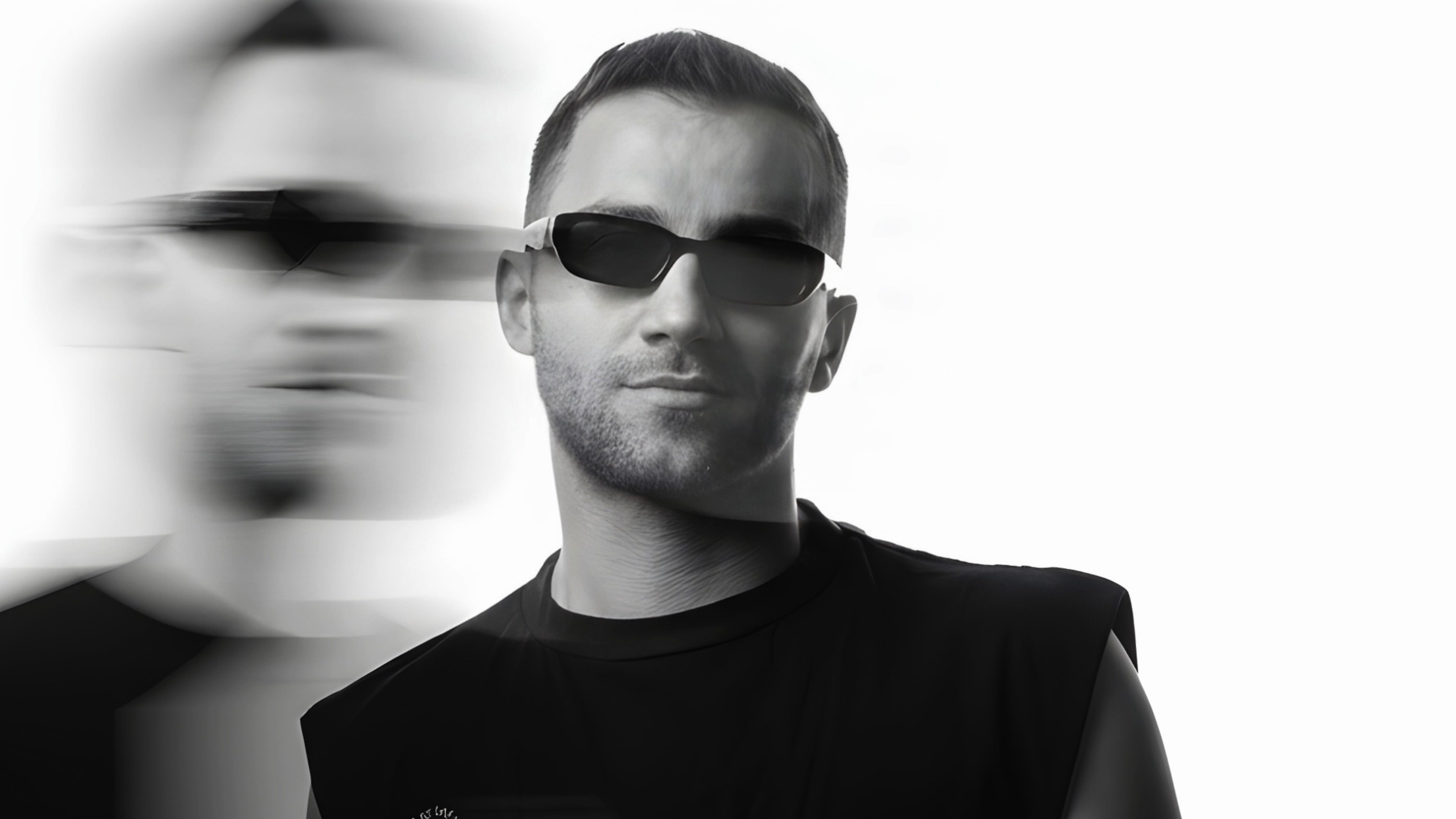 DJ schaut in die Kamera, Sonnenbrille aufgesetzt, schwarz-weiß mit Blurreffekt