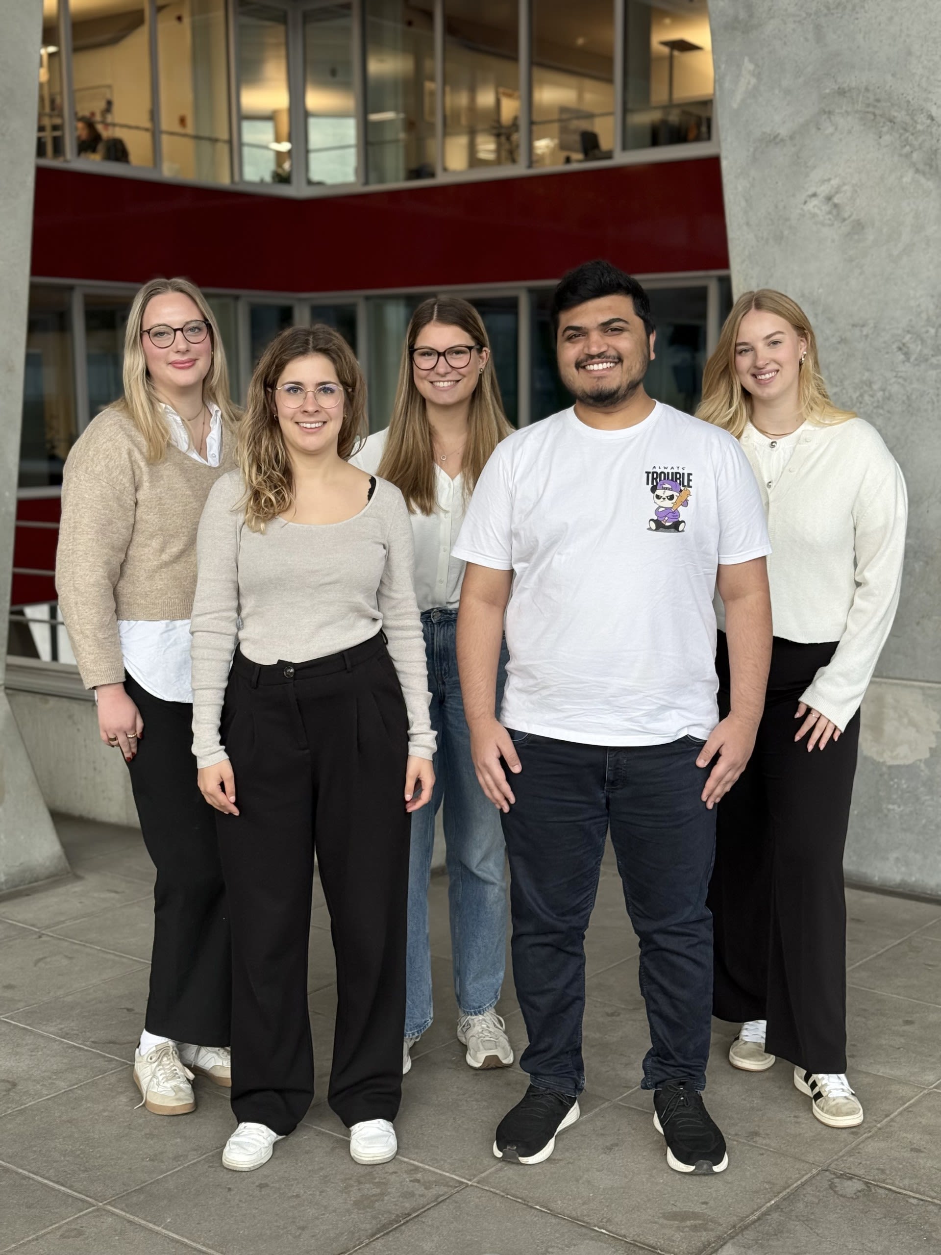 Fünf Personen, die lächelnd nebeneinander gehen