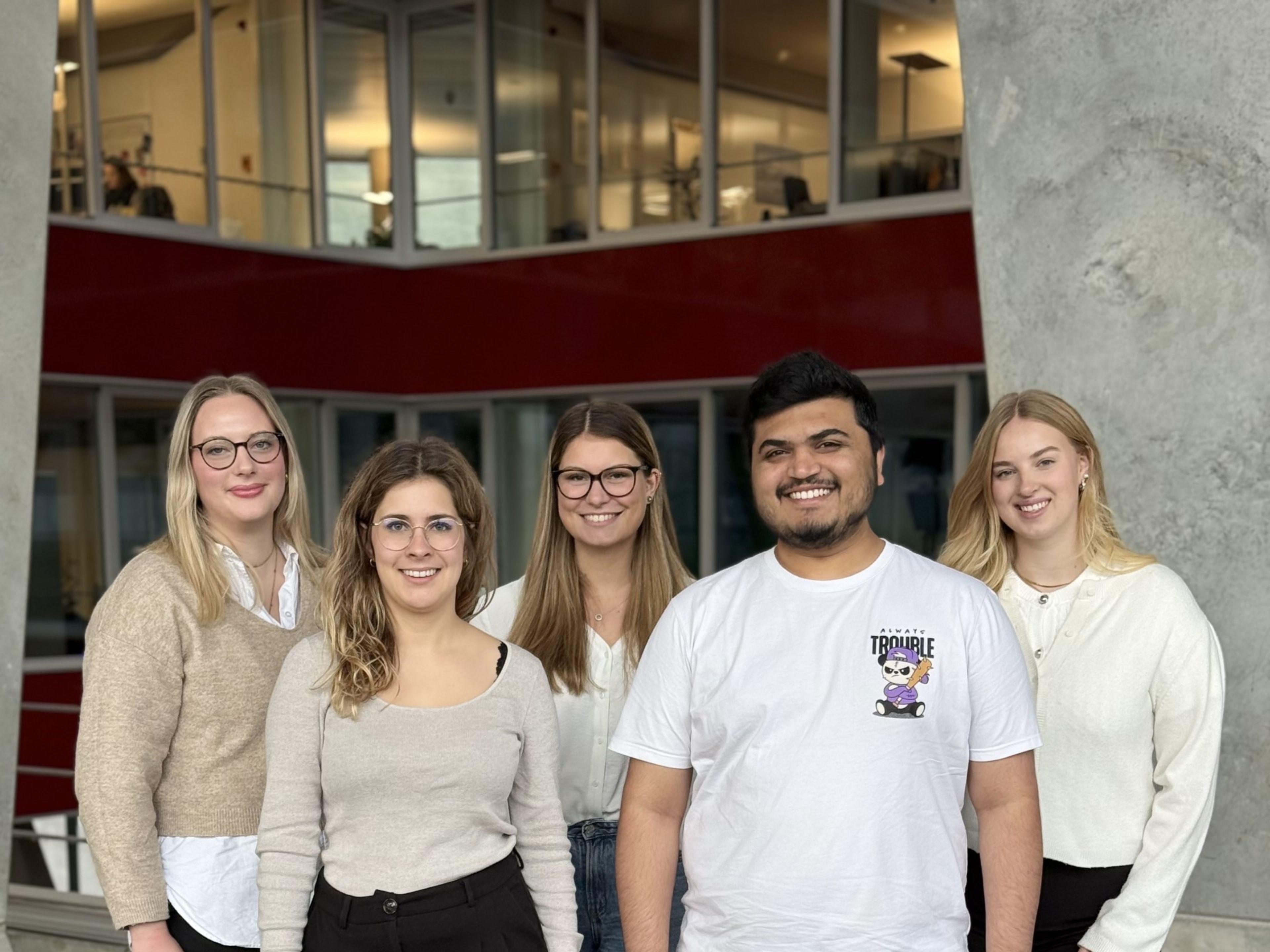 Fünf Personen, die lächelnd nebeneinander gehen