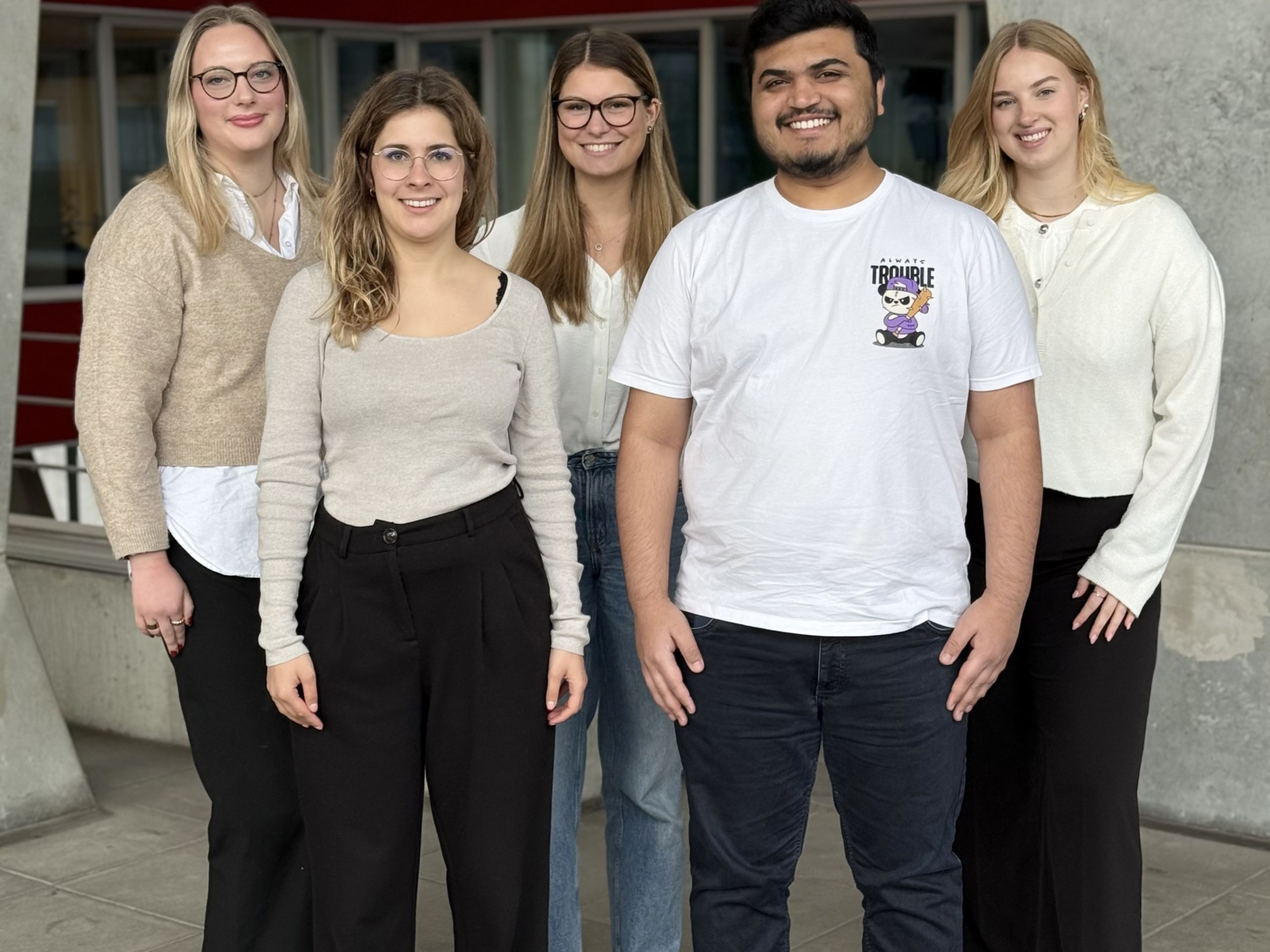 Fünf Personen, die lächelnd nebeneinander gehen