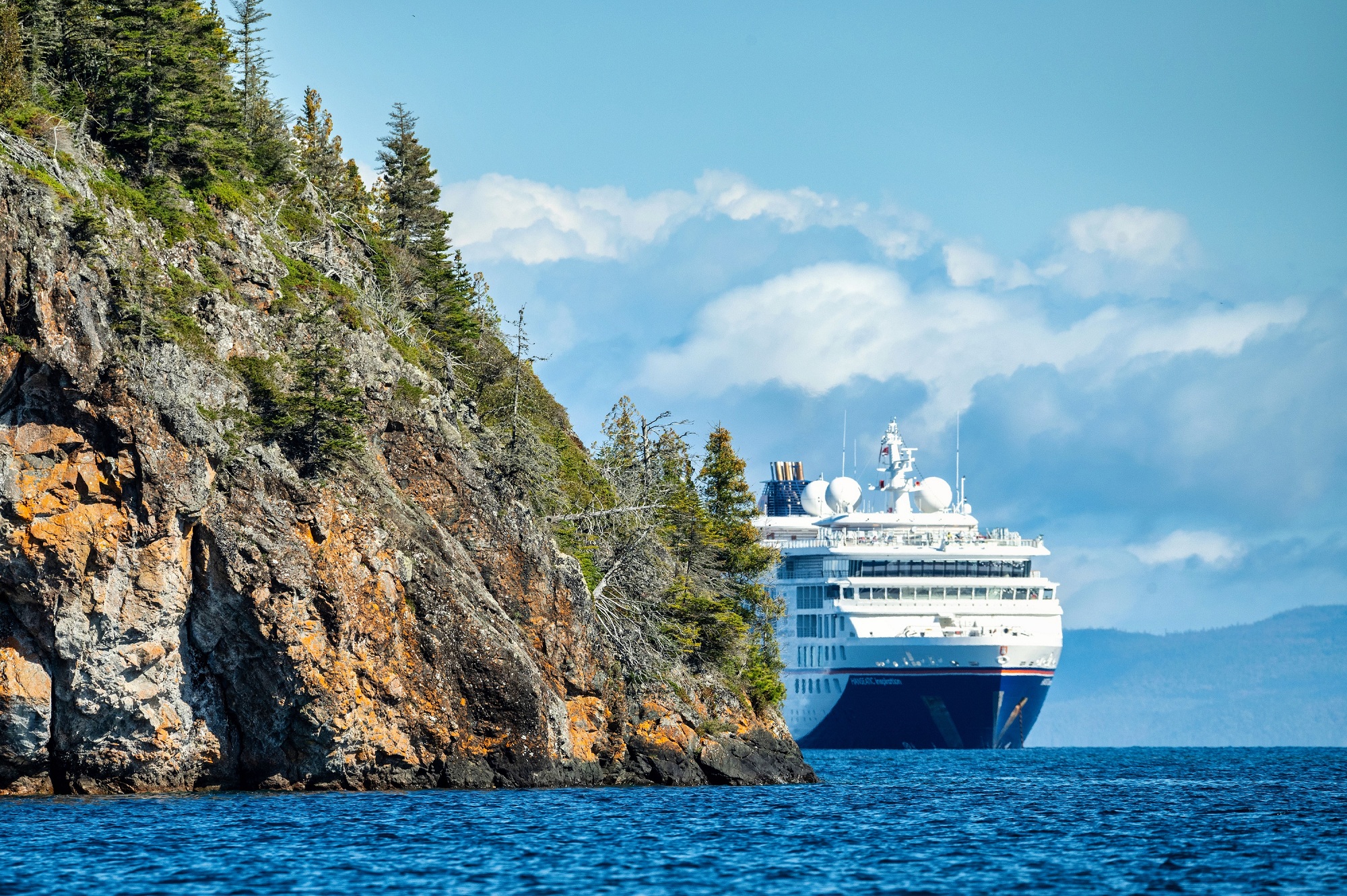 A Hapag-Lloyd Cruises expedition ship sails along a rocky coastline on one of the Great Lakes