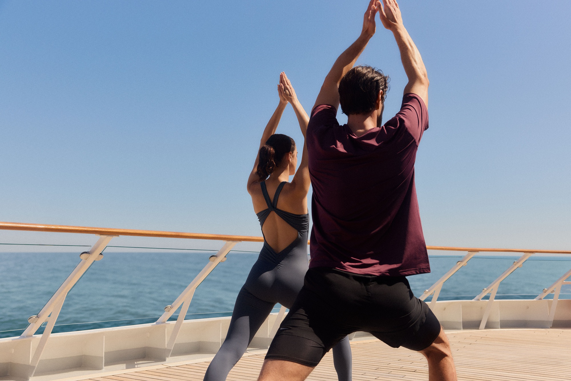 Two people practicing a yoga pose on the deck of Hapag-Lloyd Cruises 