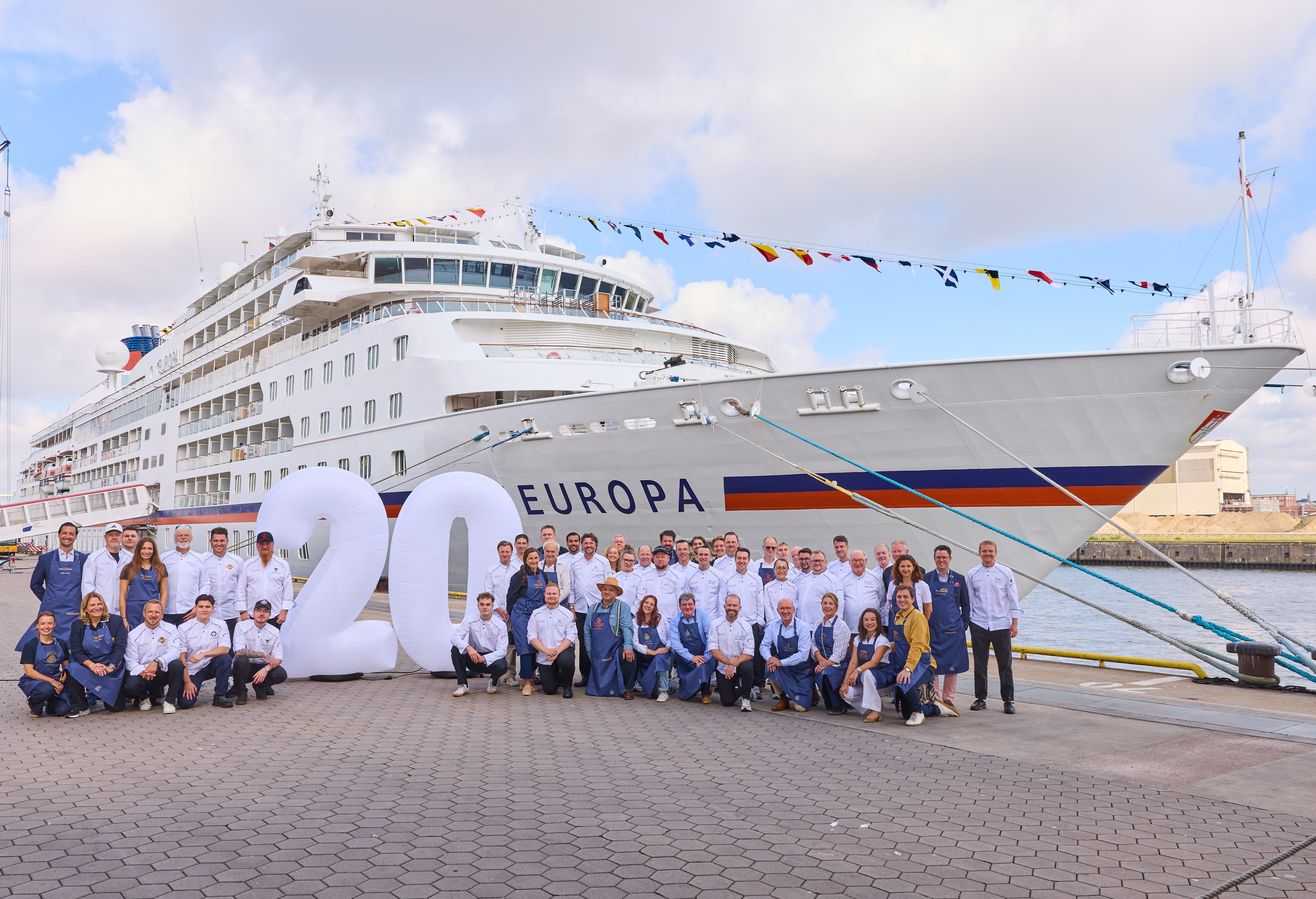 Teilnehmer von EUROPAs Beste 2026 stehen neben einer 20 vor der EUROPA in Hamburg