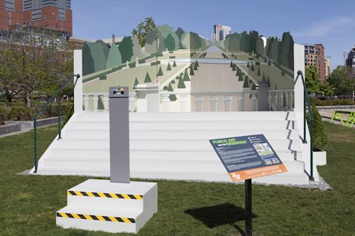 Meredith James
Far from this setting in which I now find myself, 2017
Wood, metal, and acrylic paint
Approx. 35 x 16 x 15 feet
Installation at the Rose Kennedy Greenway, Boston, MA

This sculpture is an optical illusion called an Ames Room. An Ames Room is a three-walled trapezoidal room built with a false perspective so it appears square and regular from one viewpoint while people inside the room seem to be different sizes depending on where they stand.